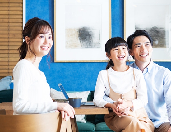 マンションの一室でくつろぎながら微笑む家族