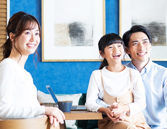 マンションの一室でくつろぎながら微笑む家族