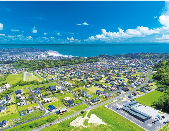 海岸線を持つ町の空からの視点。緑豊かな景観が広がる。